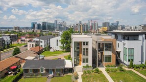 Un quartier résidentiel moderne, avec des maisons contemporaines, un ciel dégagé et une vue lointaine sur les gratte-ciel de la ville.