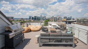 Une terrasse sur le toit équipée d’un barbecue, d’un espace salon et offrant une vue panoramique sur la ville.