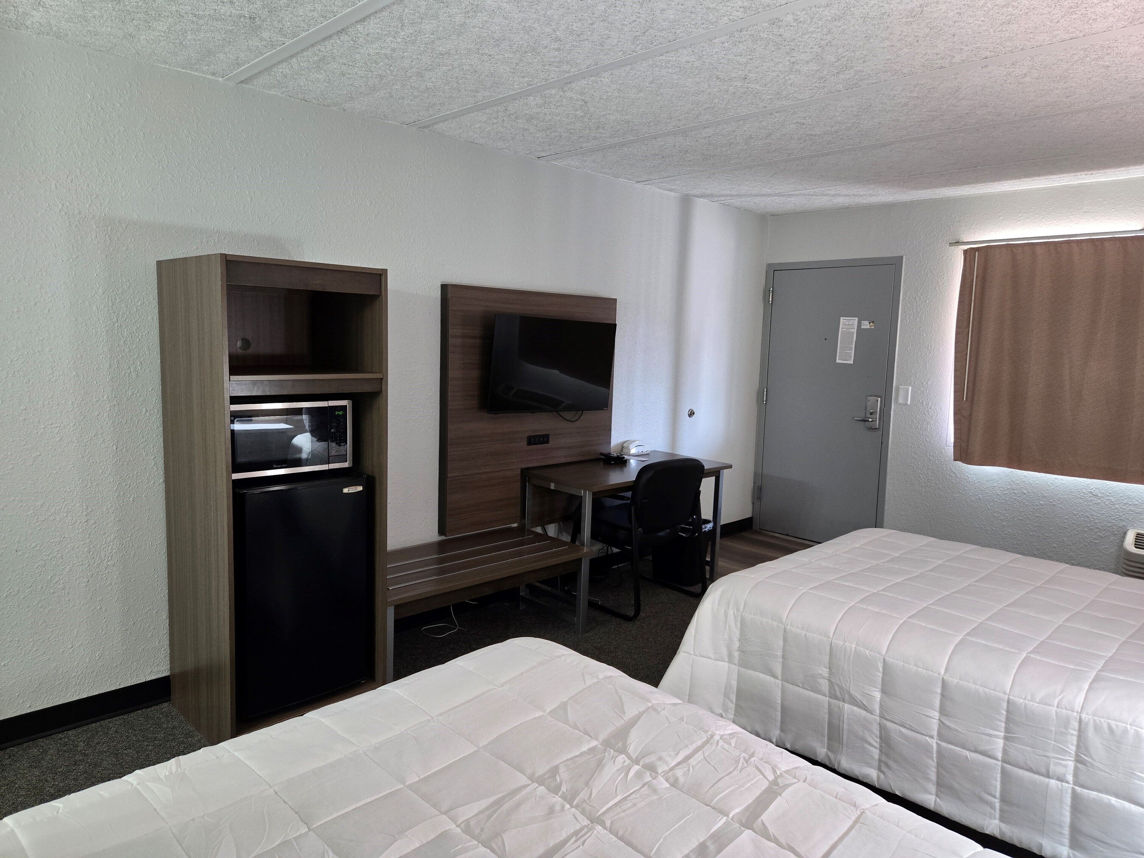 Une chambre d’hôtel avec deux lits, un bureau, une télévision et un mini-bar.