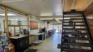 En restaurang med en bardisk, en klocka, en tavla och en trappa.