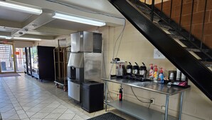 Ett professionellt kök med rostfria köksmaskiner, en kaffestation och en trappa.