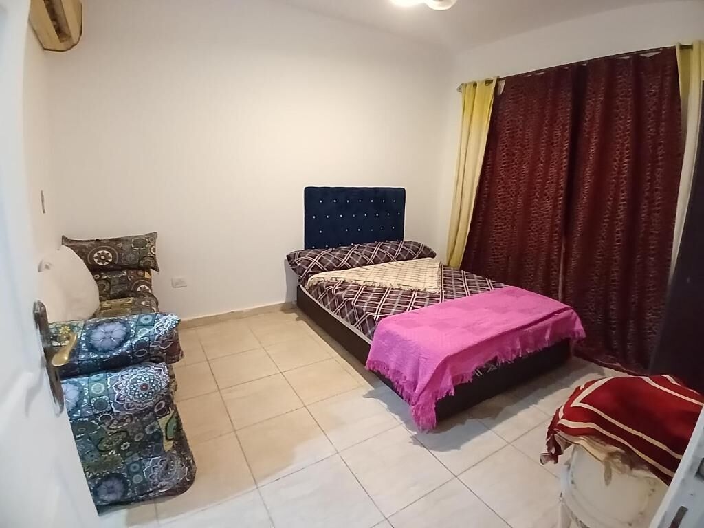 A bedroom with a bed, a chair, and a small table.