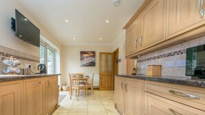 A modern kitchen with wooden cabinets, a built-in TV, and a dining area with a table and chairs.
