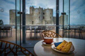 Une table avec une part de gâteau et une tasse de café, donnant sur un château historique.