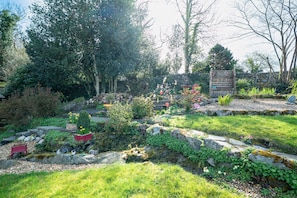 A garden with a stone wall, a wooden bench, and various plants.