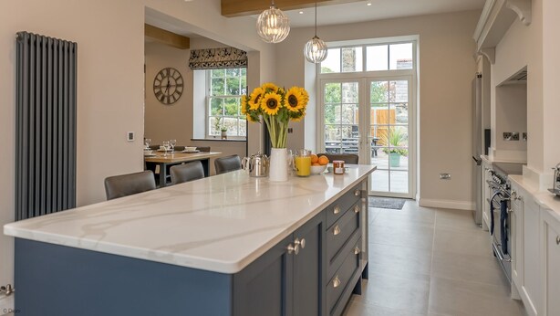 A modern kitchen with a large island, pendant lights, and a view to the outside. - Beautiful Farmhouse Accommodation in a Country Setting | Hendre-Feinws (PWLLHELI)