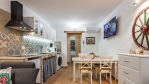 A compact kitchen with a dining area, a sofa, and a TV mounted on the wall. - La casa di Rosa 1833 by Wonderful Italy (Syracuse)