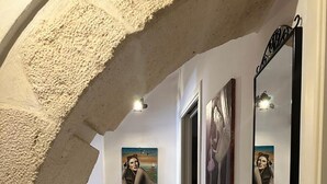 A hallway with white walls, a tiled floor, and framed artwork on the walls. - La casa di Rosa 1833 by Wonderful Italy (Syracuse)