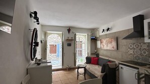 A compact kitchen with a dining area, a small refrigerator, and a window with a view of the outside. - La casa di Rosa 1833 by Wonderful Italy (Syracuse)