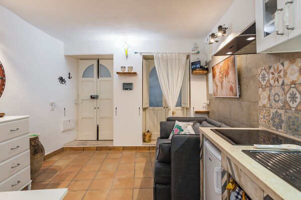 A compact kitchen with a built-in oven, a sink, and a dining area with a sofa. - La casa di Rosa 1833 by Wonderful Italy (Syracuse)