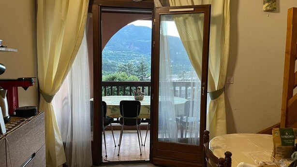 Una stanza con un letto, un tavolo con sedie, una macchina del caffè e vista su un balcone con tavolo e sedie all'esterno.