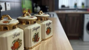 A kitchen counter with four ceramic containers labeled Tea, Sugar, and Coffee. - Luxury Holiday Apartments (Manchester)