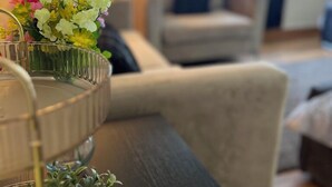 A living room with a sofa, a coffee table with a vase of flowers, and a lamp. - Luxury Holiday Apartments (Manchester)