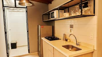 Een koelkast, een microgolfoven, kookgerei, borden en bestek