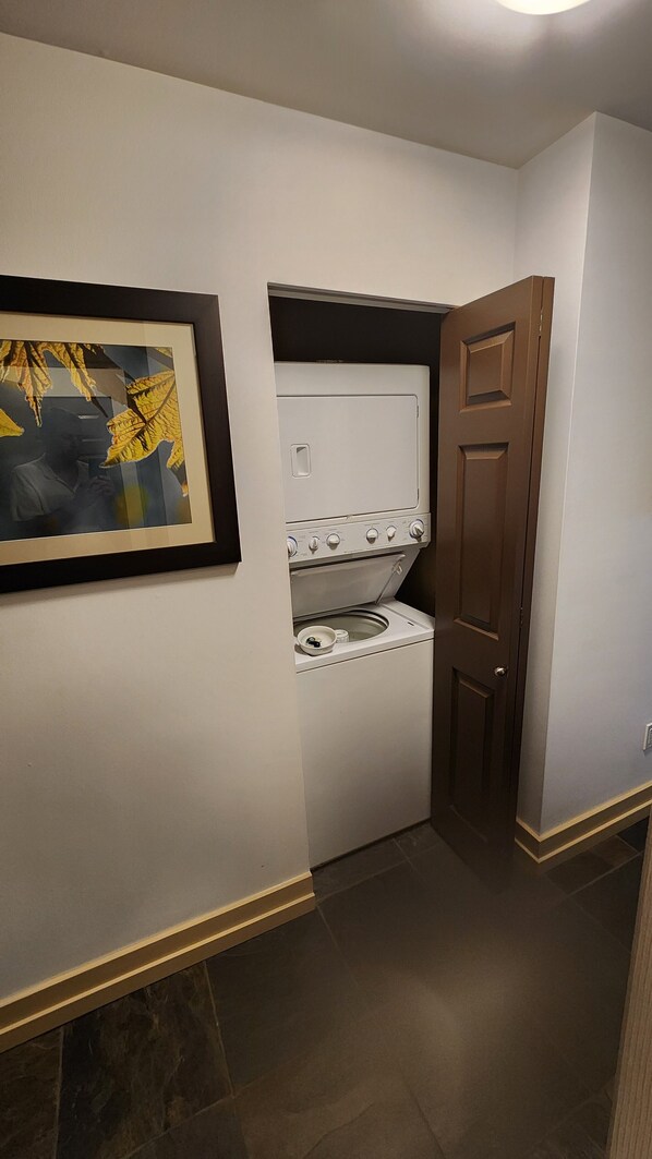 Un lavadero con lavadora y secadora, una puerta y un cuadro en la pared.