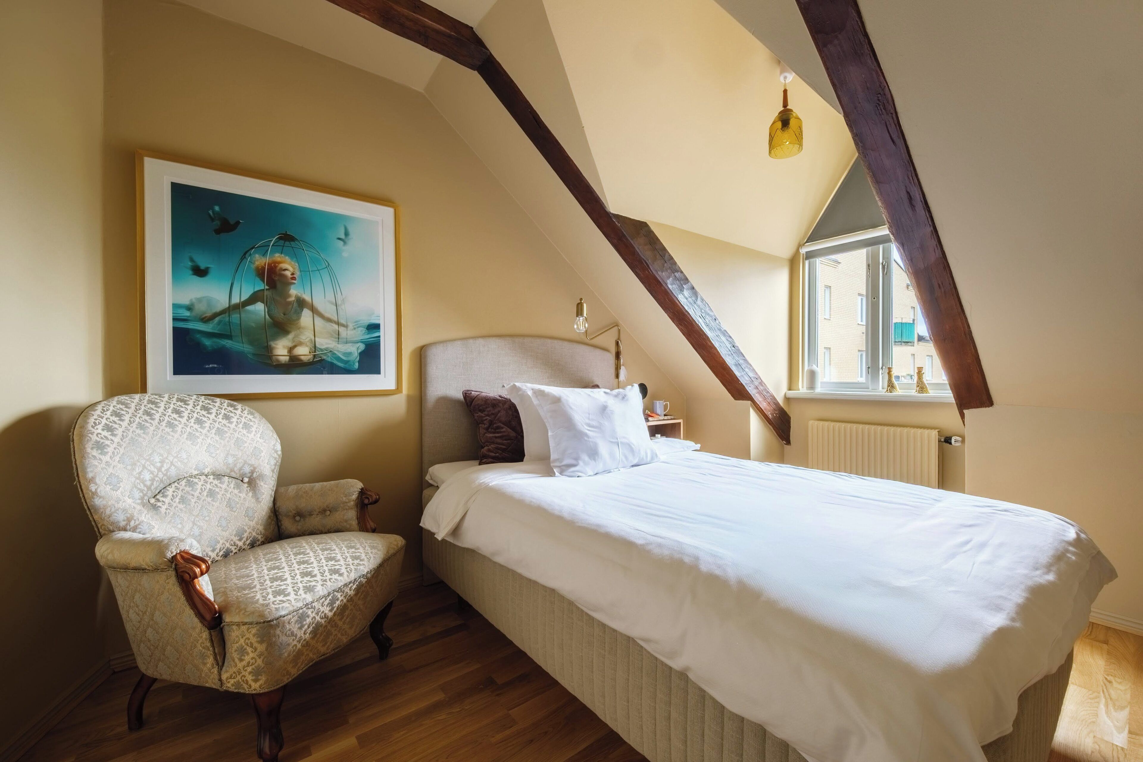 Une chambre à coucher avec un lit, une chaise, un tableau et une fenêtre.