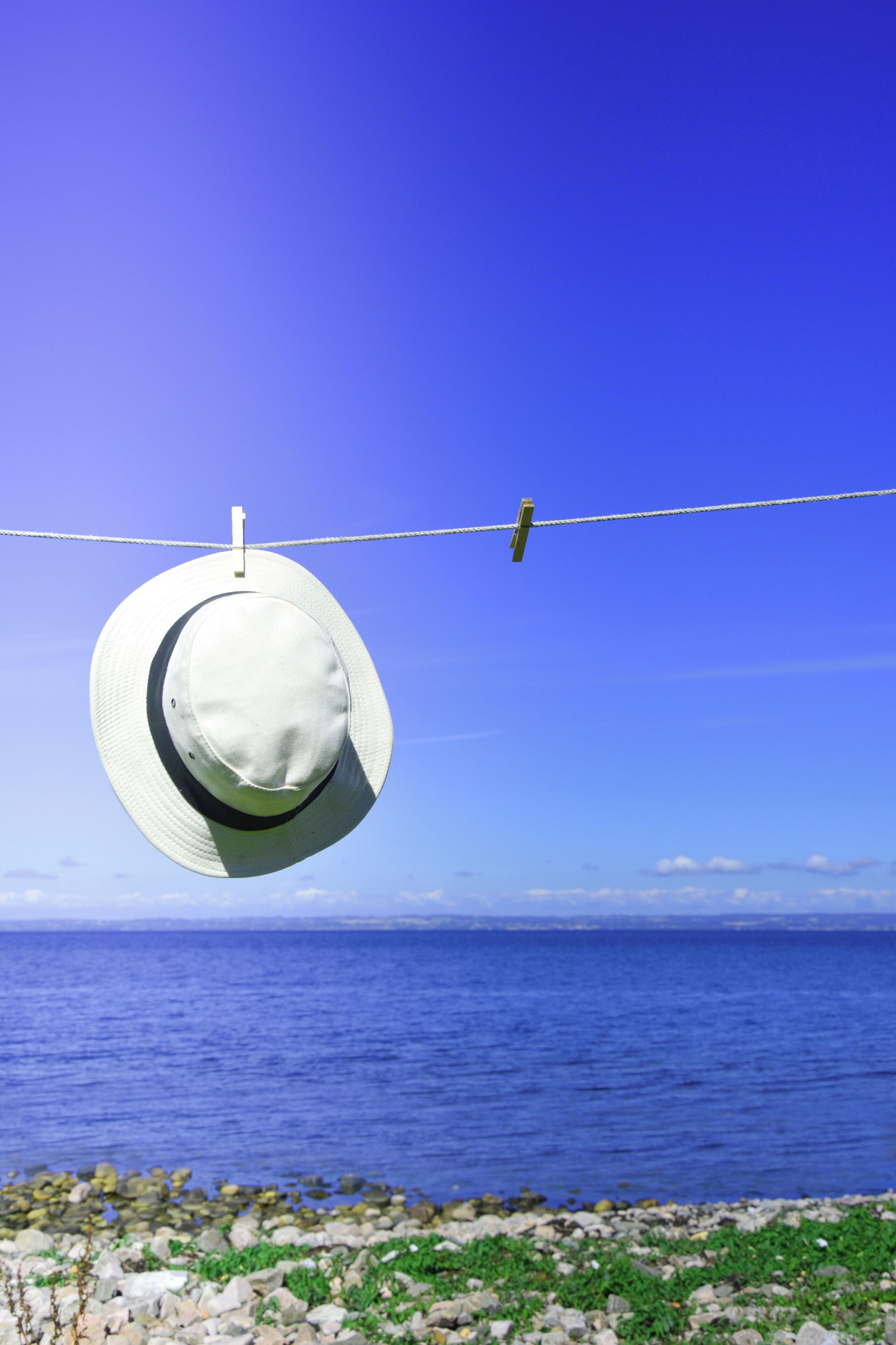 Un sombrero blanco colgado en un tendedero contra un cielo azul despejado.