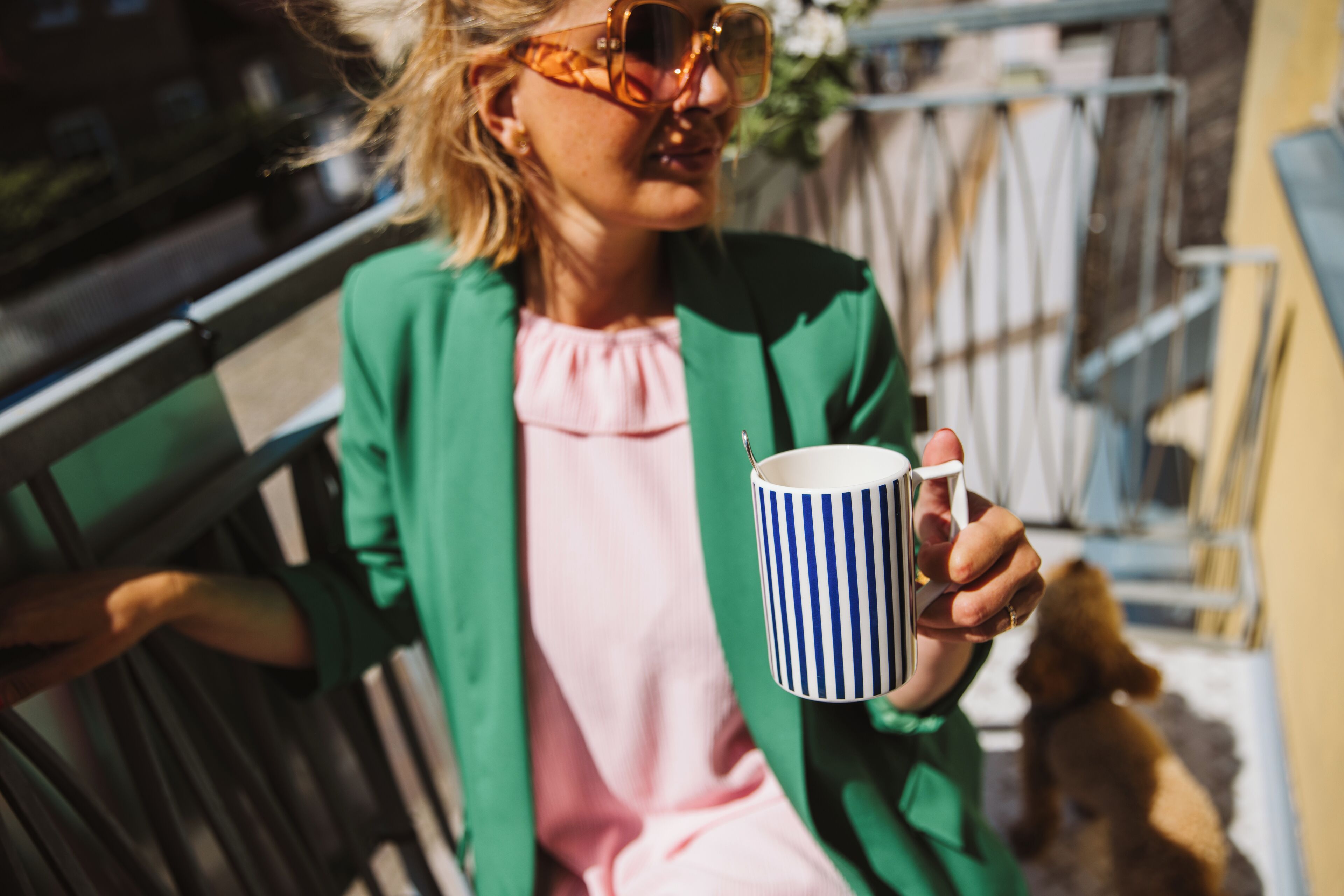 A person sitting on a bench holding a striped mug.