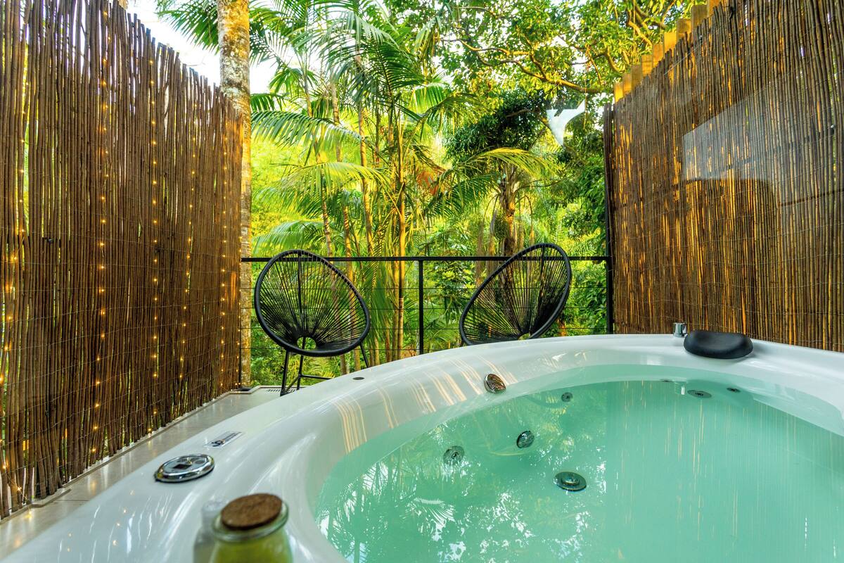 A hot tub surrounded by bamboo walls and tropical foliage.