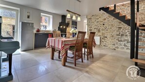 Une cuisine moderne avec un coin repas, un mur en pierre et un escalier.