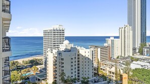 A high-rise hotel with multiple floors, a beach view, and a parking area with cars. - Central Twin Apartment with Ocean View - Q-Stay (Surfers Paradise)