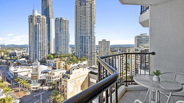 A balcony with a view of tall buildings, a clock hotel, and a street with palm trees. - Central Twin Apartment with Ocean View - Q-Stay (Surfers Paradise)