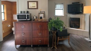 A compact kitchen with a microwave, coffee maker, and a small dining area with a chair and table. - Loblolly Pines Adventure Camp (Eureka Springs)