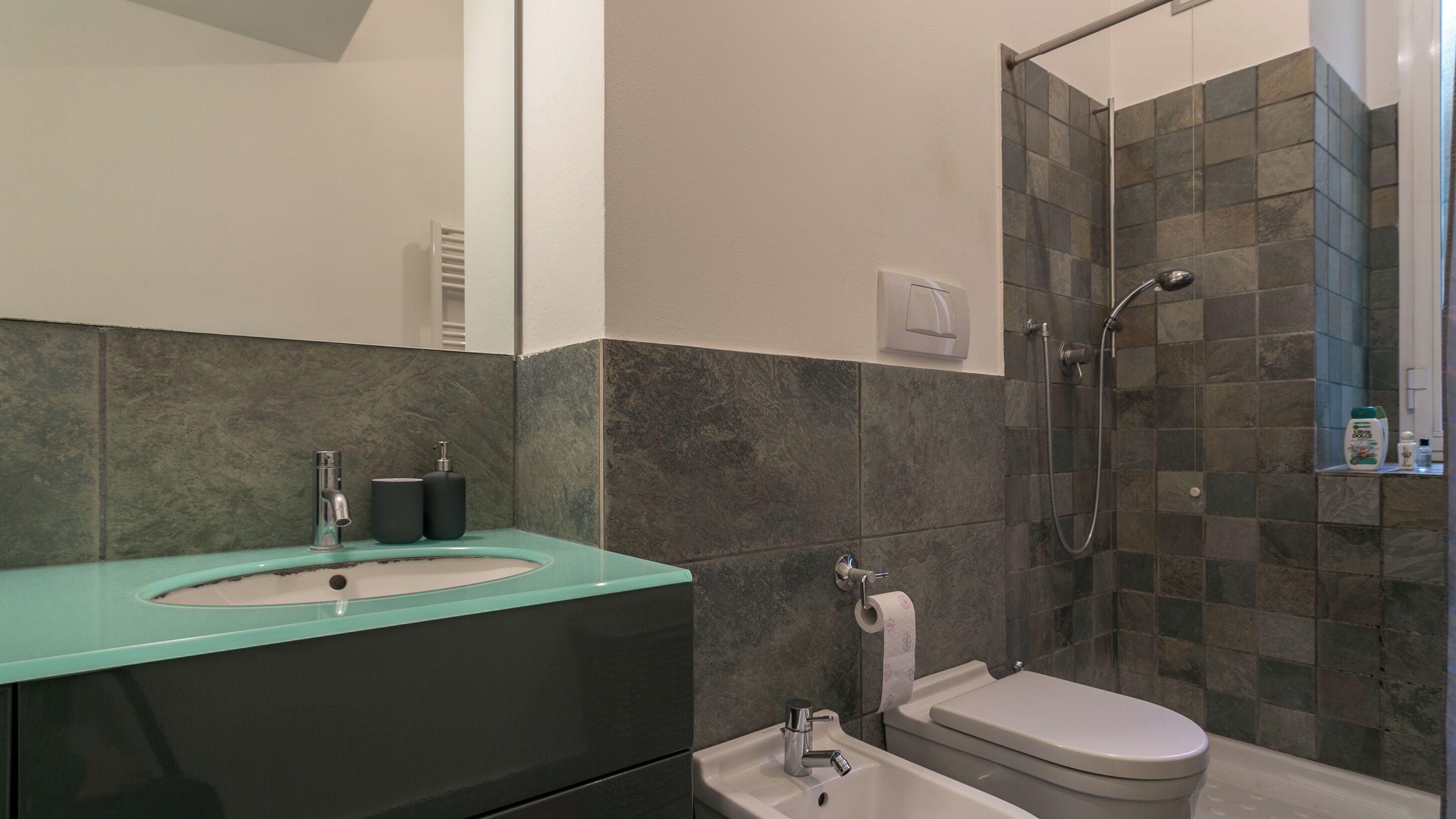 A modern bathroom with a sink, toilet, and shower.