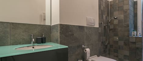 A modern bathroom with a sink, toilet, and shower.