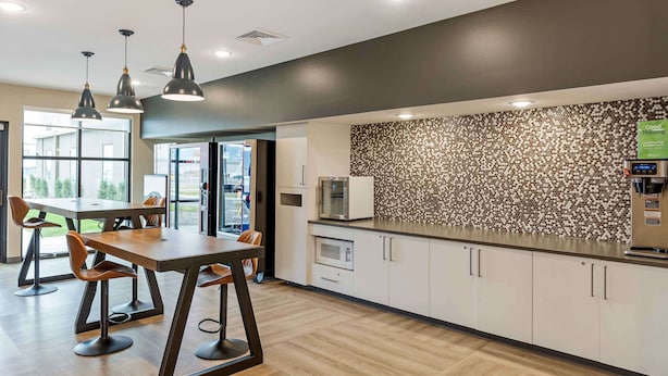 Cocina moderna con iluminación colgante, microondas y cafetera.
