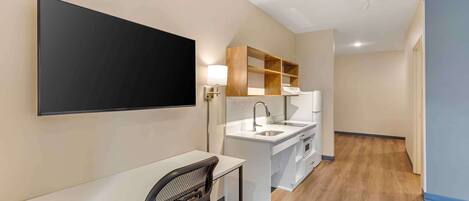A modern kitchen with a built-in stove, a sink, and a wooden shelf unit.
