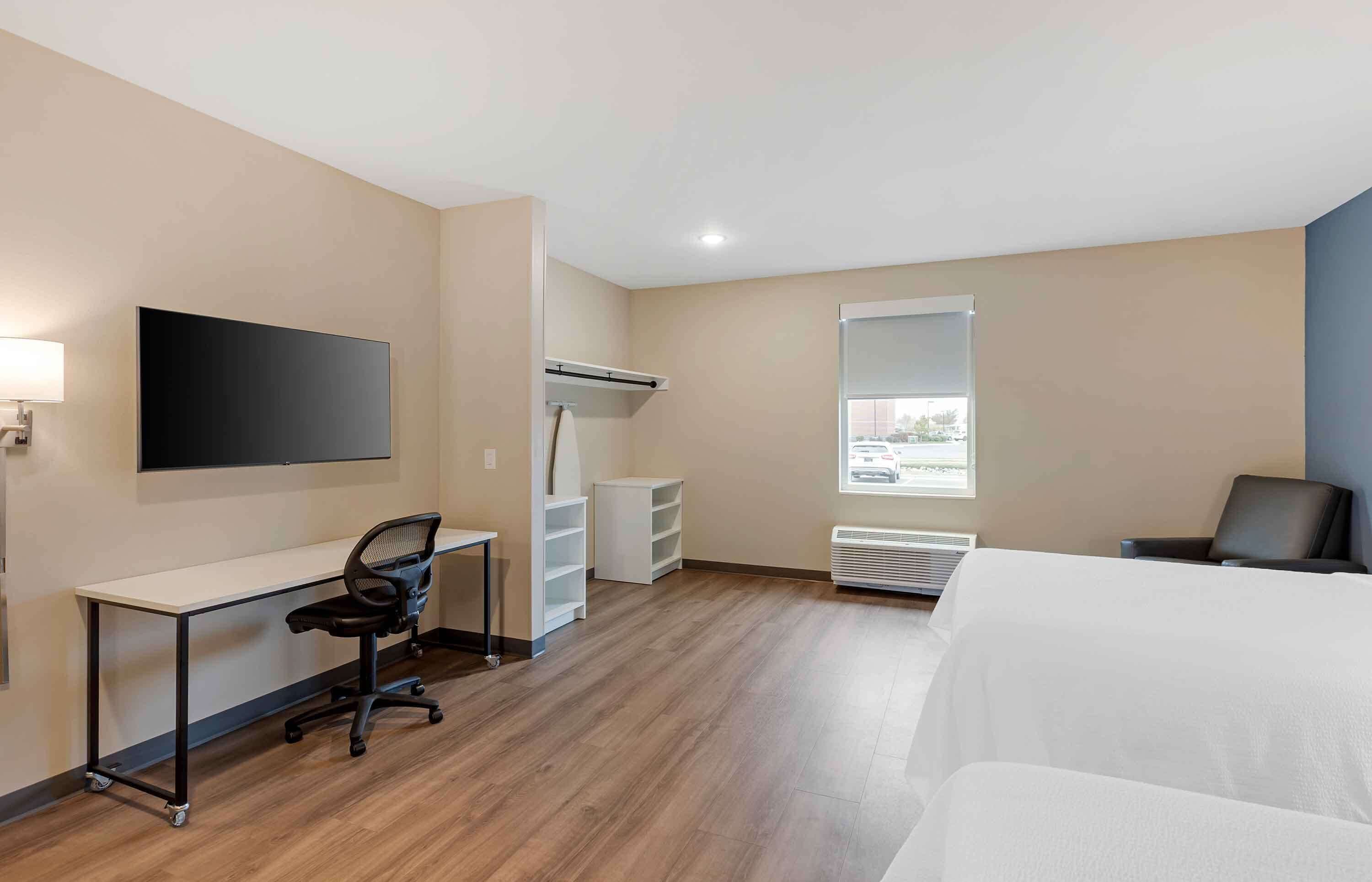 Habitació d'hotel amb escriptori, cadira, televisió, armari i llit.