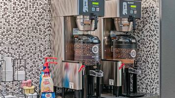 A coffee station with two Bunn coffee machines, a Nestle Coffee Mate dispenser, and a coffee bean grinder.