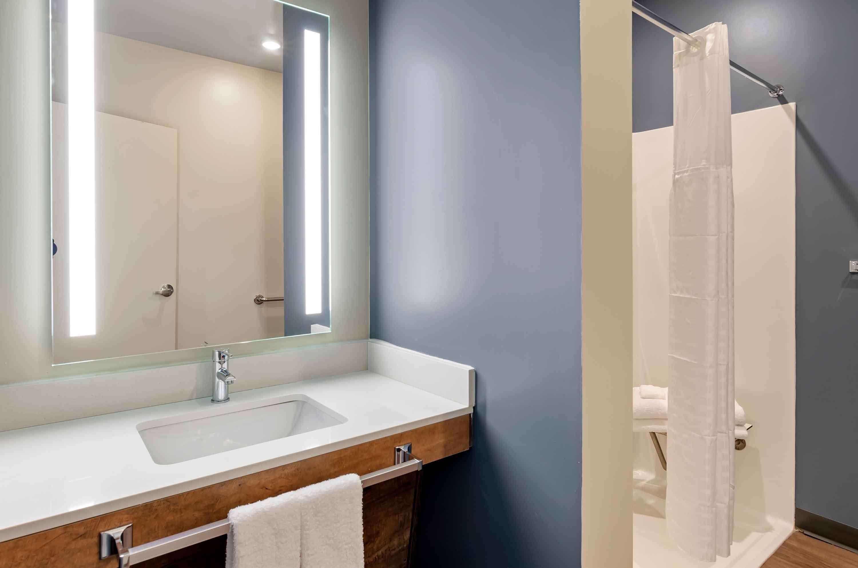 Une salle de bain avec un grand miroir, un lavabo et une douche.