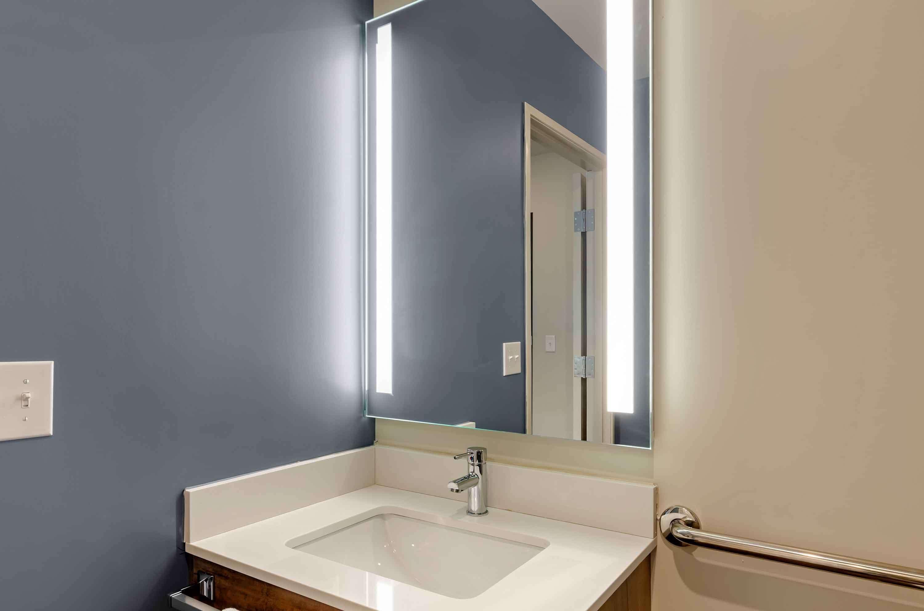 A bathroom with a white sink, a mirror, and a light fixture.