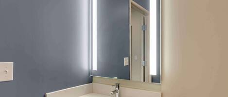 A bathroom with a white sink, a mirror, and a light fixture.