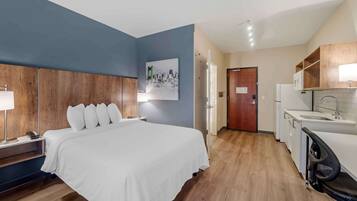 A hotel room with a bed, bedside table, lamp, and a painting on the wall.