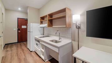 A modern kitchen with white cabinetry, a double sink, and a built-in oven.