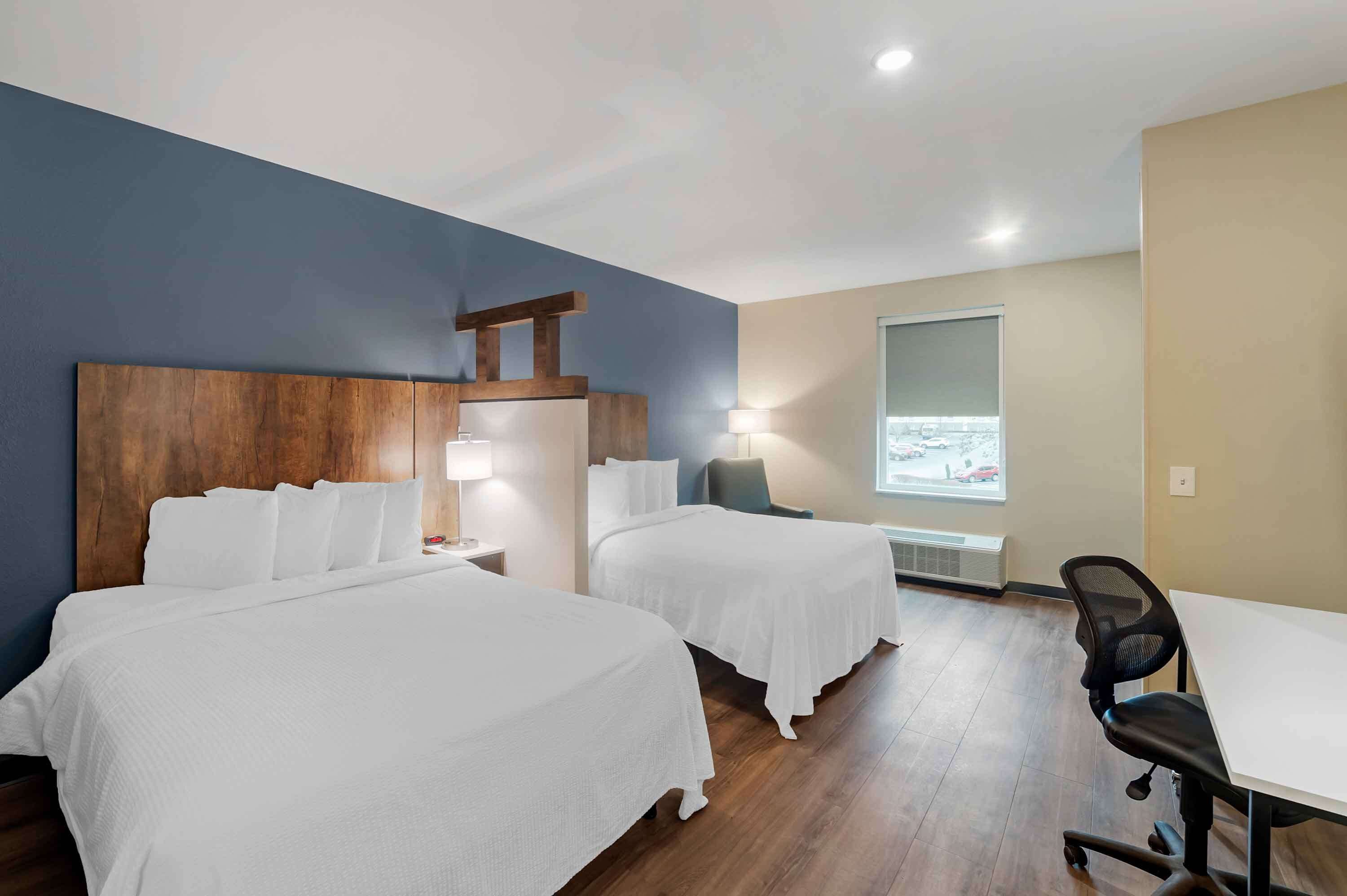 Habitación de hotel con dos camas, un escritorio y una silla.