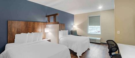 Habitación de hotel con dos camas, un escritorio y una silla.