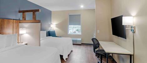 A hotel room with two beds, a desk, a chair, a TV, and a window with a view.