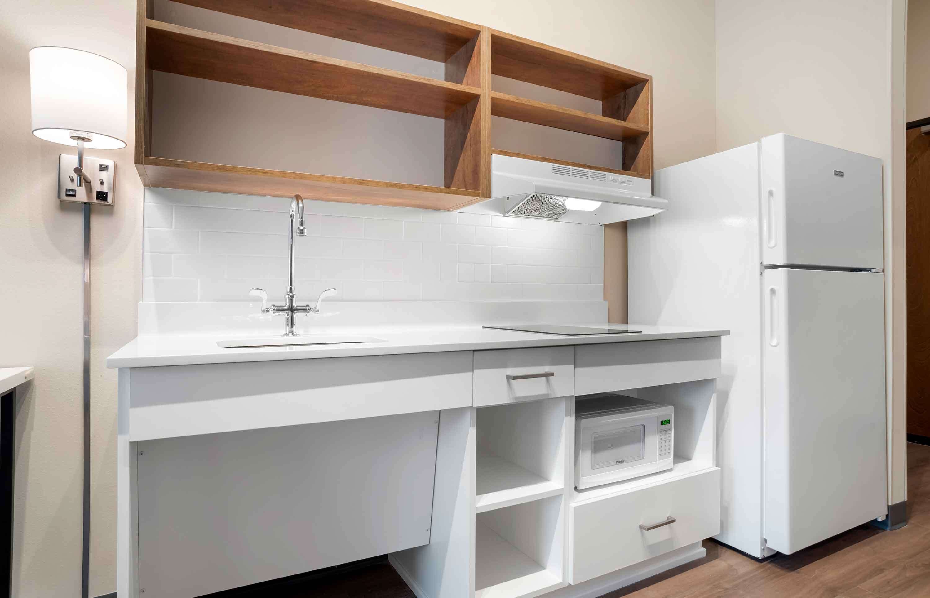 A modern kitchen with white cabinetry, a built-in microwave, and a white refrigerator.