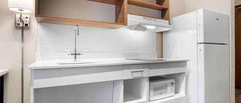 A modern kitchen with white cabinetry, a built-in microwave, and a white refrigerator.