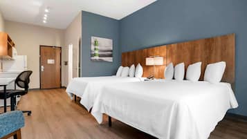 A hotel room with two beds, a desk, and a chair.