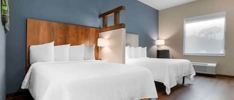 A hotel room with two beds, a wooden headboard, a large window with a view, and a ceiling fan.