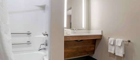 Un baño con bañera, lavabo, espejo y toallero.