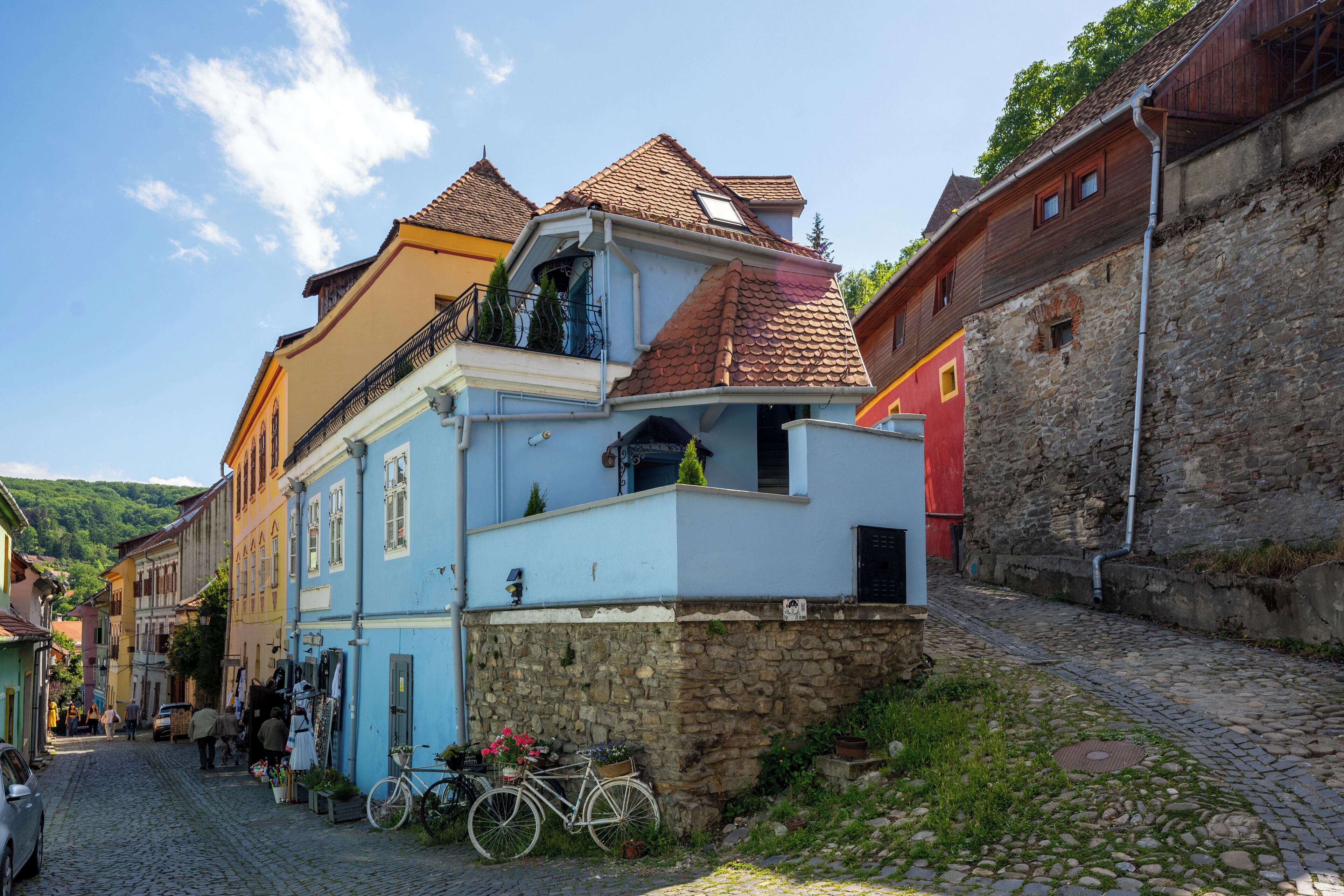 Una calle adoquinada con edificios históricos, una bicicleta y un muro de piedra.