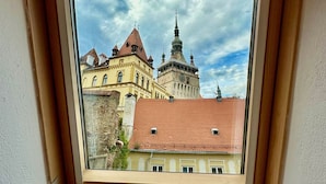 A skylight window overlooking a historic building with a clock tower and red-tiled roofs. - Blue House Citadel Sighisoara (Sighisoara)