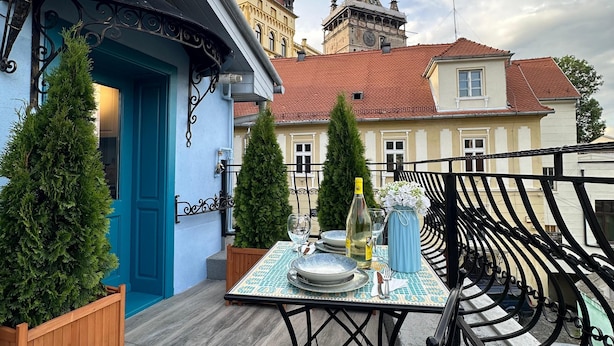 A rooftop terrace with a table set for dining, a blue door, and a view of historic buildings in the background. - Blue House Citadel Sighisoara (Sighisoara)