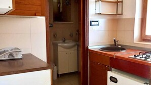 A compact kitchen with a refrigerator, stove, sink, and wooden cabinets. - Apartment Tea 2 close to the beach and city center (Umag)